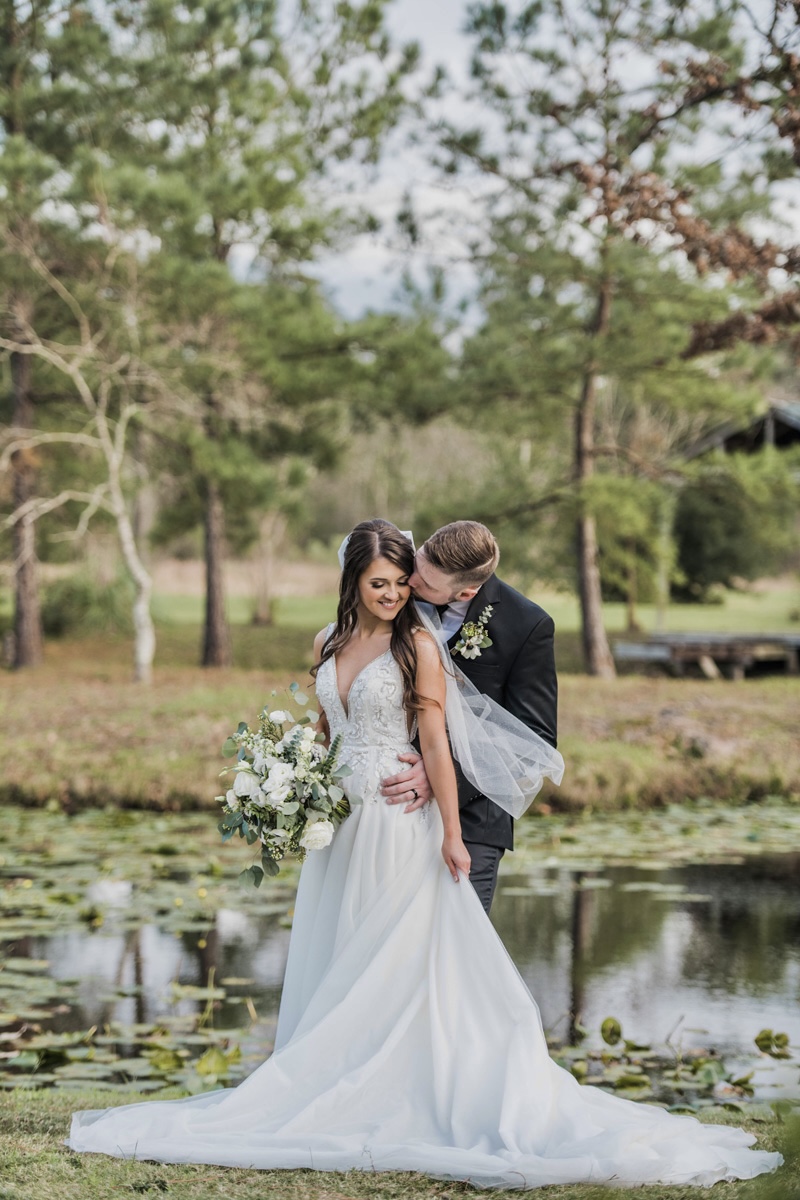 married couple stands in front of pond